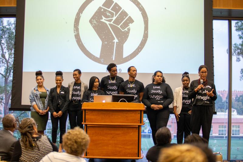 Eight students on stage looking towards one female speaker