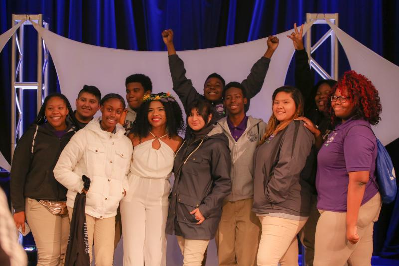 Eleven students smiling and posing for a photo on stage at MLK Oratorical